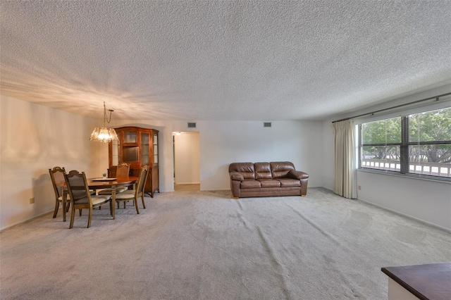 living room featuring visible vents, light carpet, a textured ceiling, and an inviting chandelier