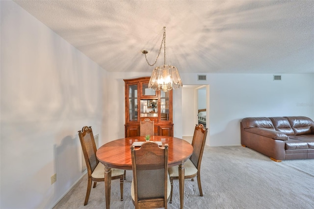 dining room with light carpet, visible vents, and a textured ceiling