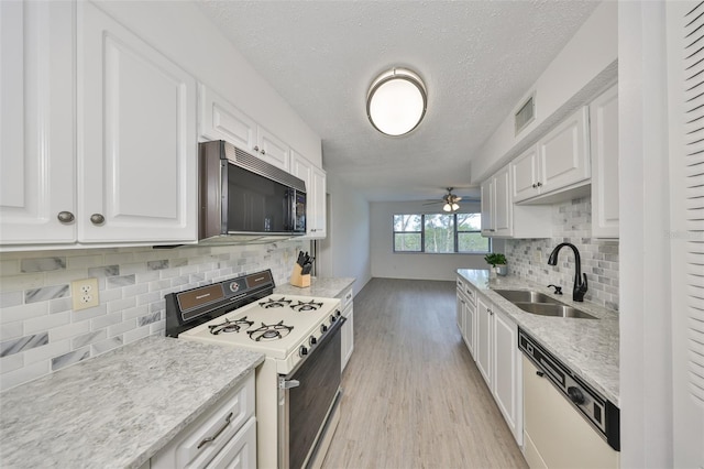 kitchen with white appliances, white cabinetry, light countertops, and a sink