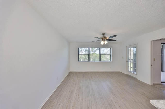 empty room with a ceiling fan, light wood finished floors, and a textured ceiling