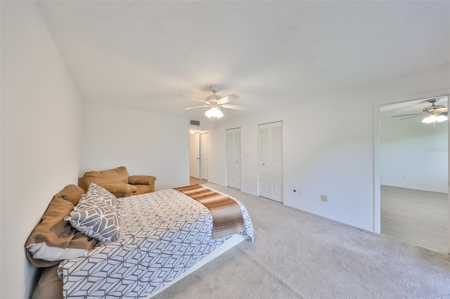 bedroom with visible vents, multiple closets, carpet, and ceiling fan