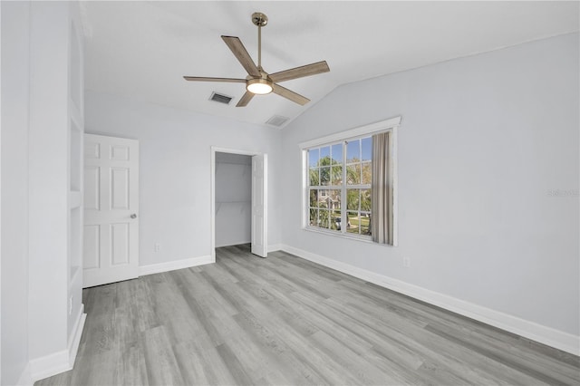 unfurnished bedroom featuring visible vents, wood finished floors, a closet, baseboards, and vaulted ceiling