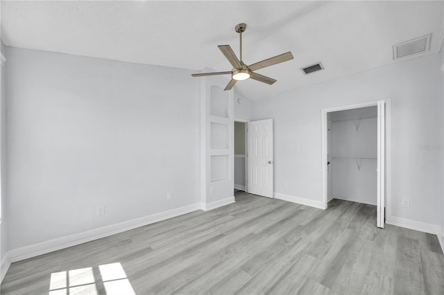 unfurnished bedroom with visible vents, a closet, light wood-style floors, baseboards, and vaulted ceiling