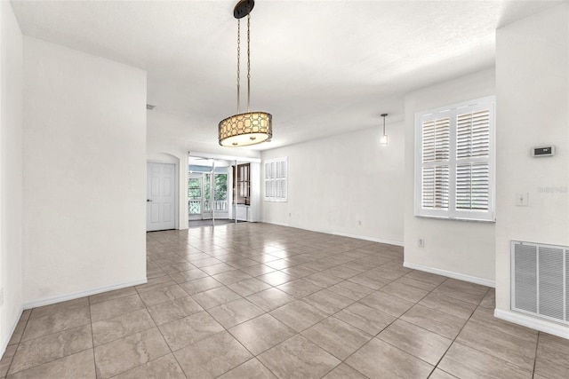 empty room featuring tile patterned flooring, baseboards, and visible vents