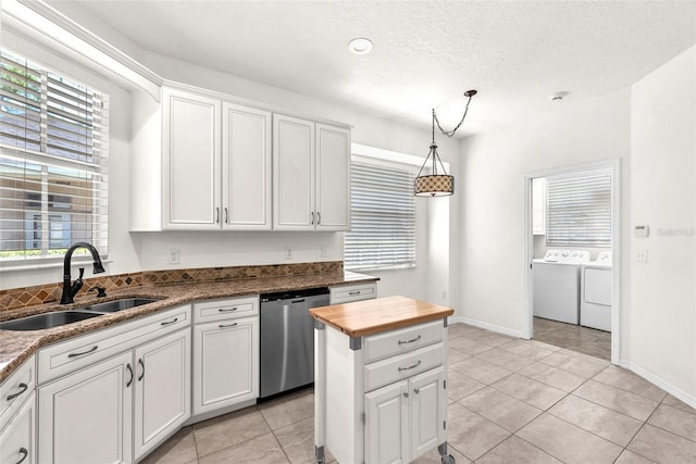 kitchen featuring a sink, washer and dryer, white cabinets, dishwasher, and hanging light fixtures