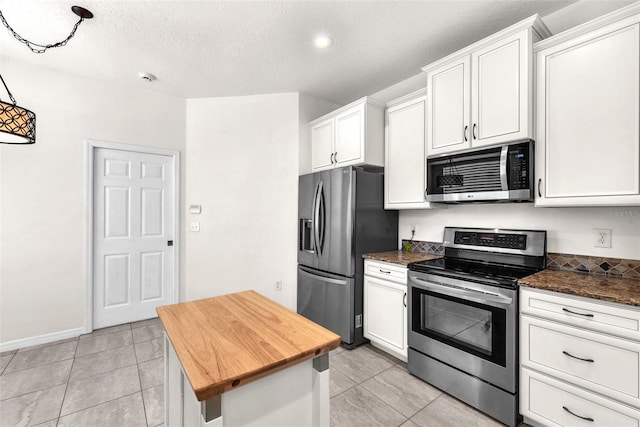 kitchen featuring a kitchen island, butcher block countertops, stainless steel appliances, a textured ceiling, and white cabinetry