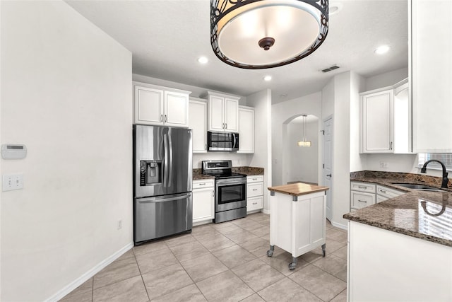 kitchen with visible vents, arched walkways, a sink, stainless steel appliances, and white cabinetry