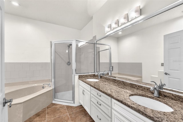 bathroom with tile patterned flooring, a stall shower, a garden tub, and a sink