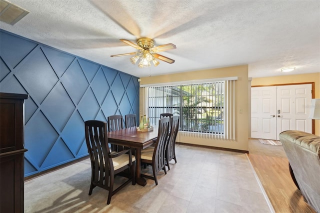 dining space with visible vents, baseboards, a textured ceiling, and a ceiling fan