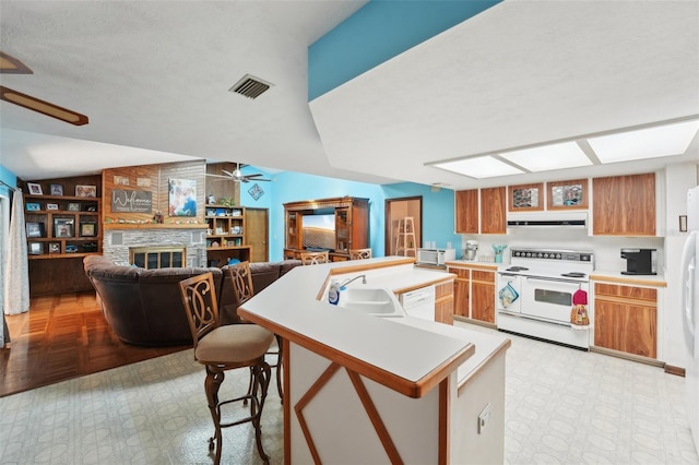 kitchen with white appliances, a ceiling fan, visible vents, a fireplace, and light countertops