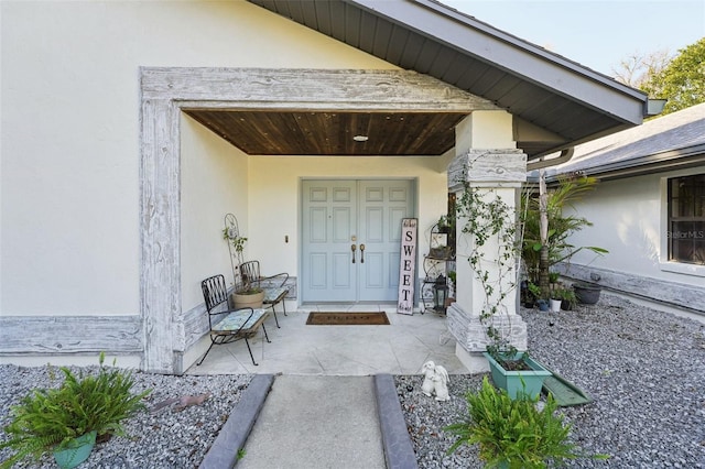 doorway to property with stucco siding and covered porch