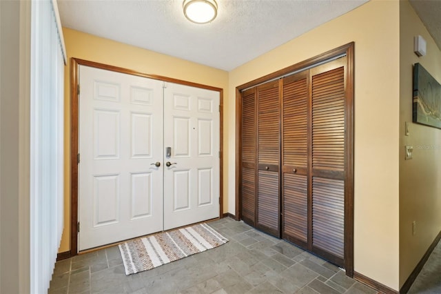 entryway featuring a textured ceiling, baseboards, and stone finish flooring