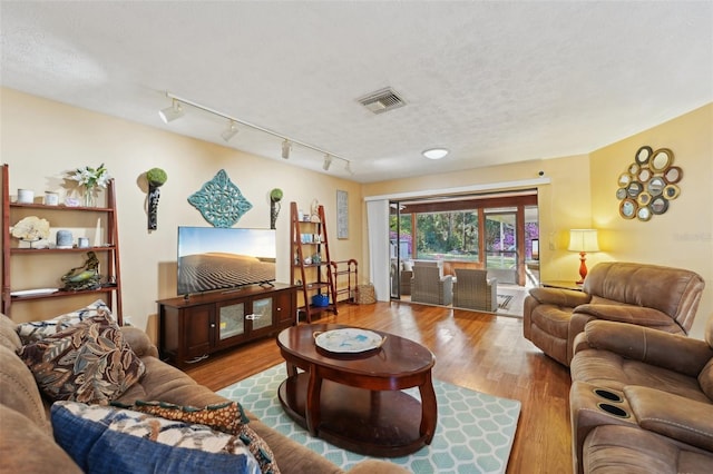 living area featuring wood finished floors, visible vents, and a textured ceiling