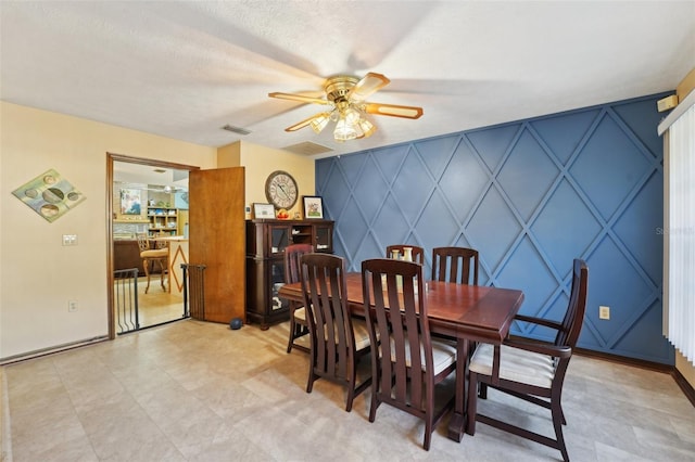 dining area featuring visible vents, ceiling fan, an accent wall, and a decorative wall