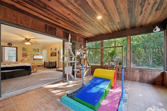 sunroom / solarium with a ceiling fan and wood ceiling