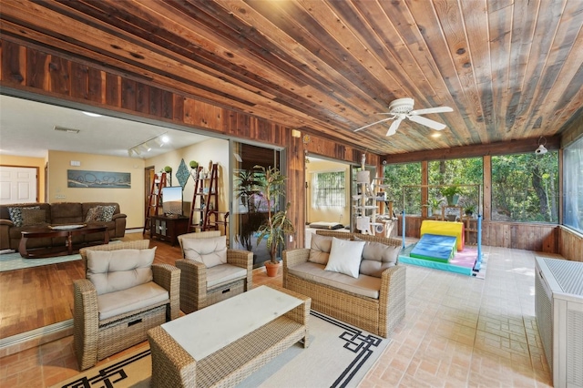 living room with plenty of natural light, wooden walls, wooden ceiling, and a ceiling fan