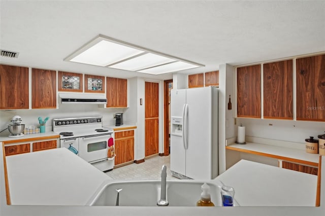 kitchen with under cabinet range hood, visible vents, white appliances, and light countertops