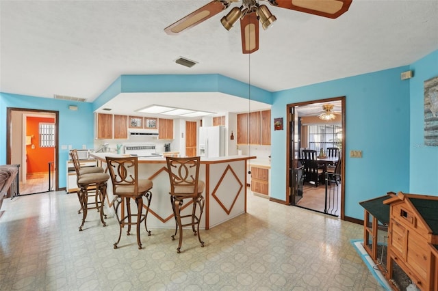 kitchen featuring range with electric cooktop, a ceiling fan, white fridge with ice dispenser, light countertops, and light floors