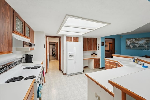 kitchen featuring under cabinet range hood, brown cabinets, white appliances, and a sink