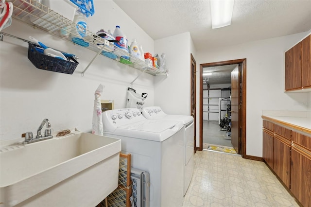 laundry area featuring independent washer and dryer, a sink, a textured ceiling, cabinet space, and light floors