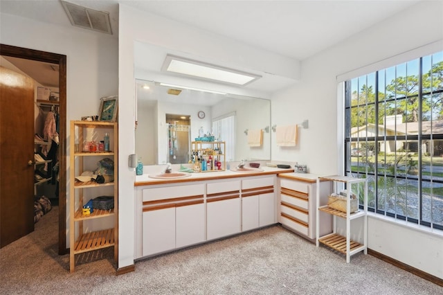 bathroom featuring a walk in closet, carpet flooring, vanity, and visible vents