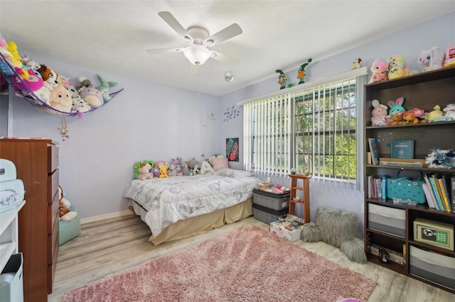 bedroom with ceiling fan, baseboards, and wood finished floors