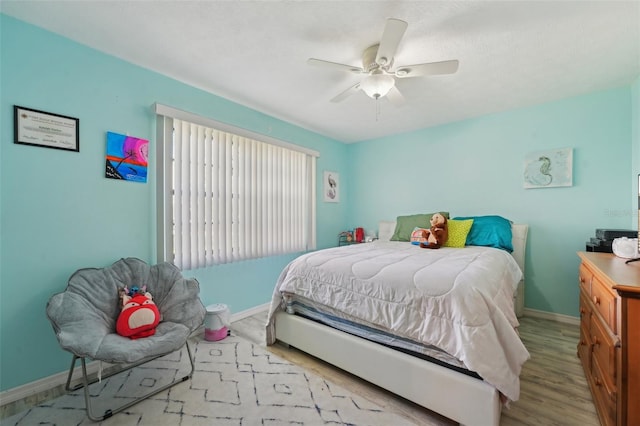 bedroom featuring ceiling fan, baseboards, and wood finished floors