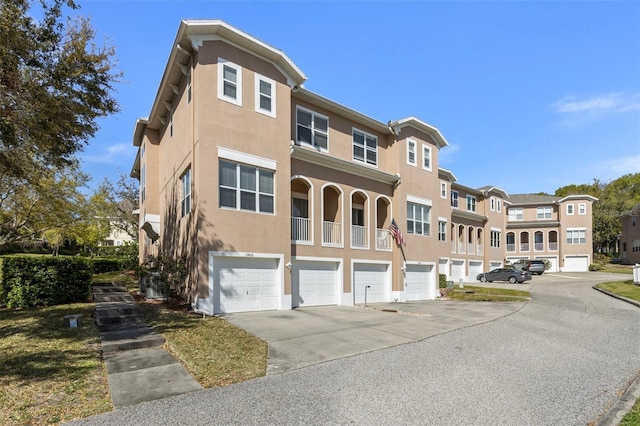 view of property featuring a residential view, stucco siding, an attached garage, and driveway