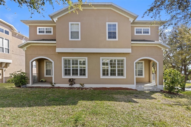 view of front of house with a front lawn, covered porch, and stucco siding