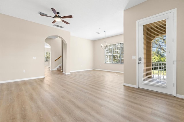 unfurnished living room featuring visible vents, arched walkways, stairway, and light wood finished floors