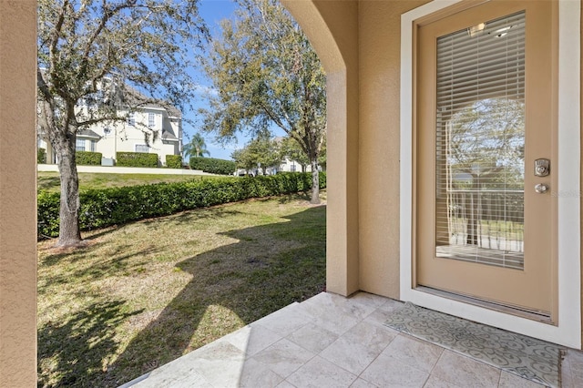 doorway to property featuring stucco siding and a yard