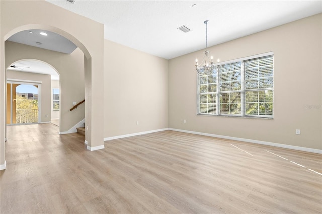 empty room featuring visible vents, light wood-type flooring, and baseboards