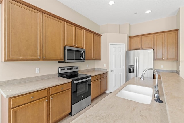 kitchen with recessed lighting, a sink, stainless steel appliances, light countertops, and brown cabinets