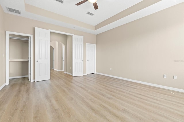 unfurnished bedroom featuring arched walkways, visible vents, and light wood-style floors