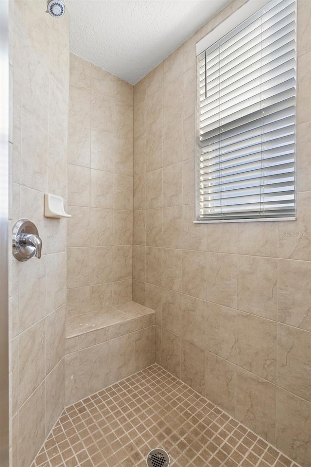 bathroom featuring a tile shower and a textured ceiling