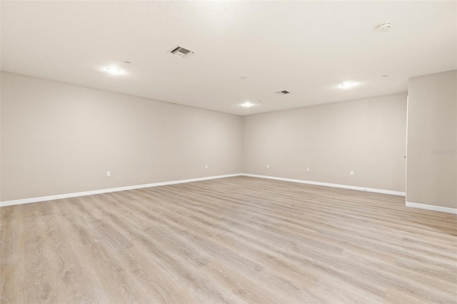 unfurnished room featuring light wood finished floors, visible vents, and baseboards