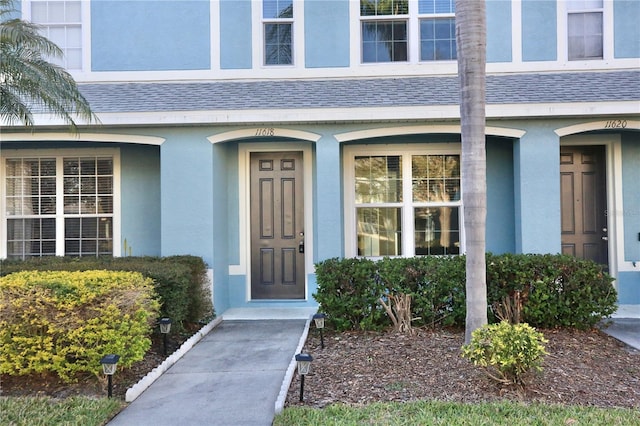 property entrance featuring stucco siding and roof with shingles