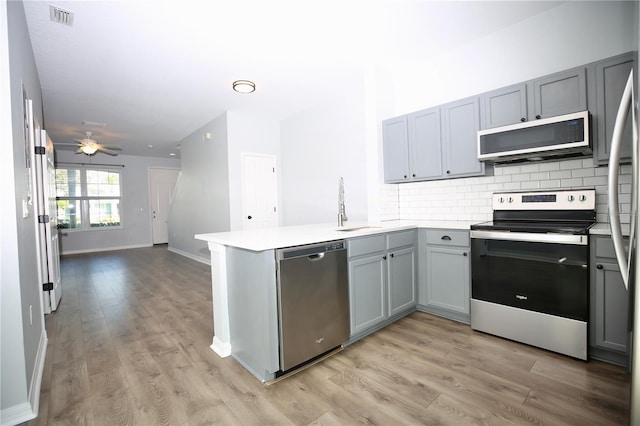 kitchen with visible vents, gray cabinetry, appliances with stainless steel finishes, a peninsula, and a sink