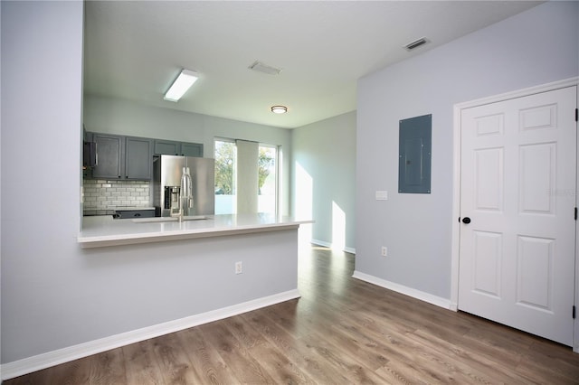 kitchen featuring visible vents, electric panel, wood finished floors, stainless steel fridge with ice dispenser, and light countertops