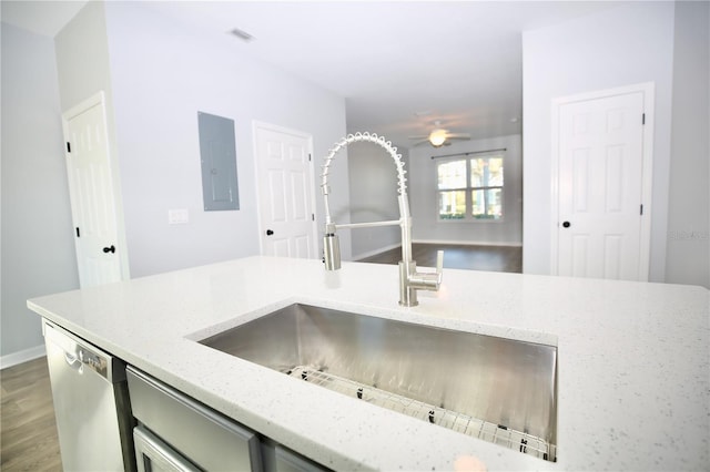 kitchen featuring light stone counters, a ceiling fan, electric panel, a sink, and stainless steel dishwasher