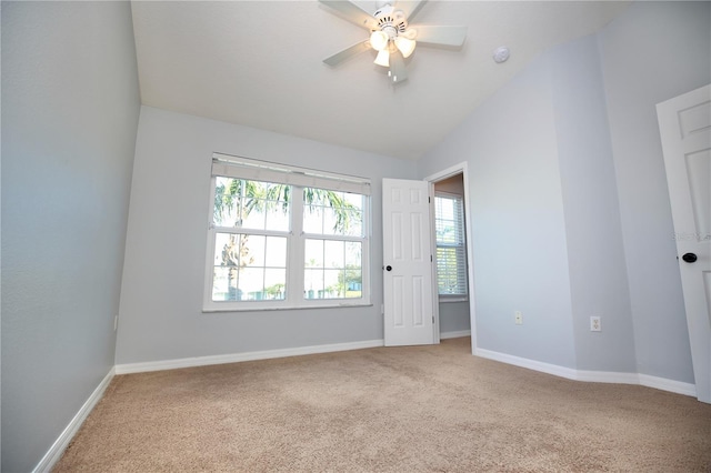 spare room featuring baseboards, carpet floors, ceiling fan, and vaulted ceiling