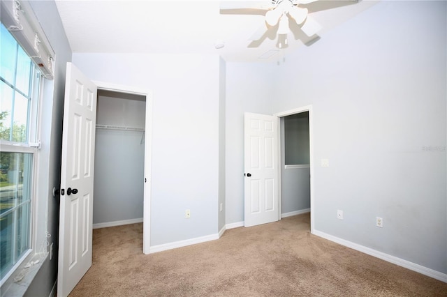 unfurnished bedroom featuring a walk in closet, a closet, baseboards, and carpet floors