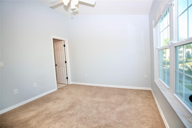 empty room with a towering ceiling, a ceiling fan, baseboards, and carpet floors