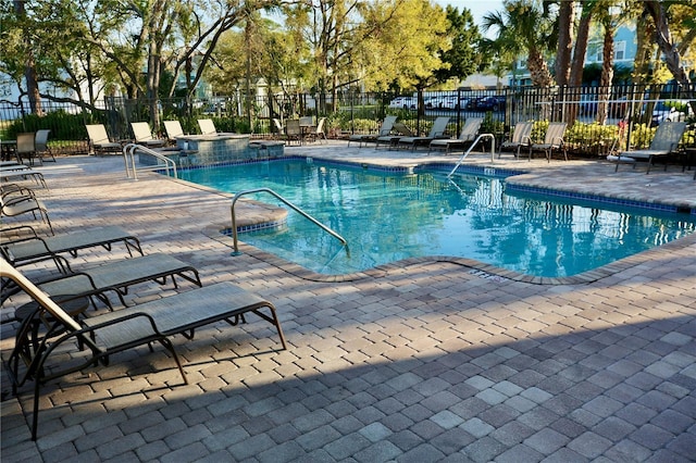 pool with a patio area and fence