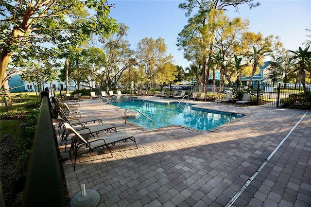 community pool with a patio area and fence