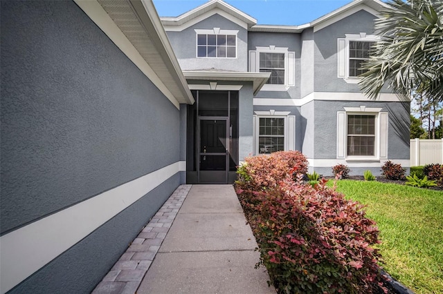 doorway to property with stucco siding and a yard