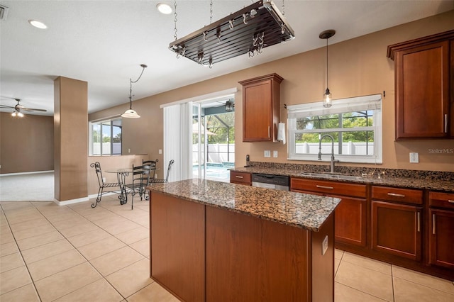 kitchen featuring a ceiling fan, dishwasher, a sink, light tile patterned floors, and dark stone counters