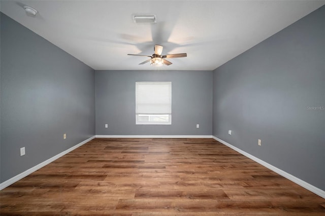 unfurnished room with visible vents, a ceiling fan, baseboards, and wood finished floors