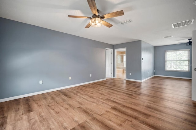 empty room featuring a ceiling fan, baseboards, visible vents, and wood finished floors