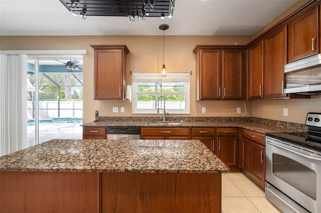 kitchen with a wealth of natural light, dark stone counters, appliances with stainless steel finishes, and a sink